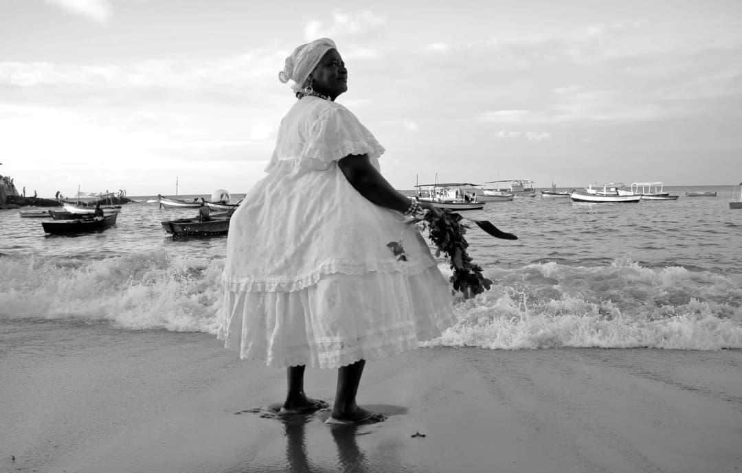 Mulher de vestido branco na praia - Consórcio Bahiana