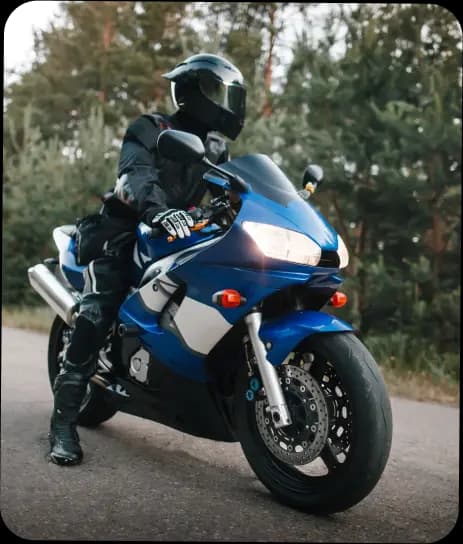 Motociclista com capacete e roupas de proteção em uma motocicleta esportiva azul em uma estrada - Consórcio Bahiana